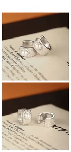 Macro detail of S925 sterling silver earrings with floral engraving and round pearl