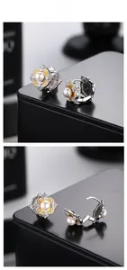 Close-up of S925 silver vintage earrings with white pearl and gold textured floral details