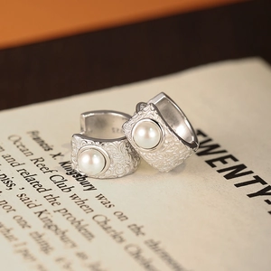 Vintage S925 silver hoop earrings with relief floral patterns and pearls on book background