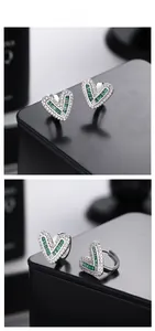 Detail of S925 silver heart hoop earrings with emerald green baguette cut stones
