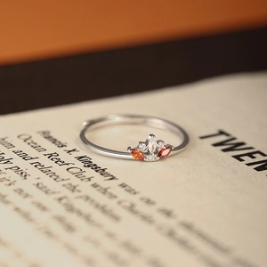 Exquisite S925 silver crown ring with orange and white gemstones on a book background