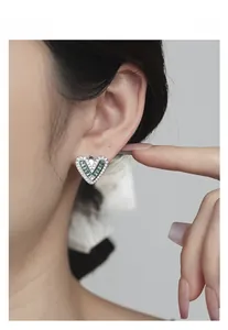 Close-up of S925 sterling silver heart earrings with green zircon and sparkling stones