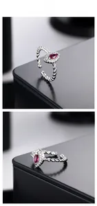 Detail of twisted silver ring with marquise red gemstone and white zircon accents