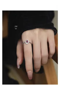 Detail of marquise-cut red ruby ring with twisted silver band worn on index finger
