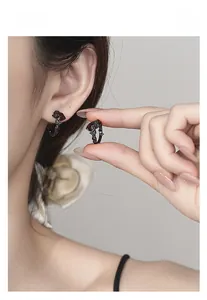 Gros plan sur des boucles d'oreilles roses noires gothiques avec zircon rouge et détails
