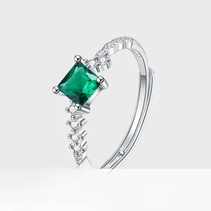 Close-up of square cut emerald ring with pavé diamond accents and silver metal band