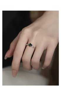 Close-up of a S925 sterling silver ring with a square emerald gemstone and micro-pavé diamonds