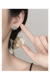 Macro view of 925 silver star stud earrings with green zircon and pink flower inlay
