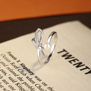 Elegant S925 silver bow ring with pearl and diamond accents on a vintage book backdrop