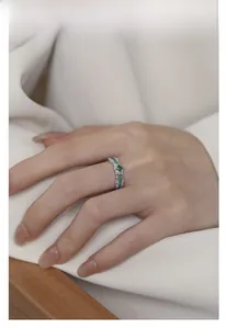 Detailed view of an S925 silver ring with green cubic zirconia and enamel on a model