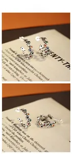 Macro detail of S925 silver C-shape earrings with colorful cubic zirconia inlay