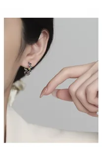 Macro view of C-shaped S925 silver earring featuring colorful gemstones and woven texture