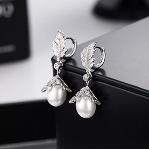 Elegant S925 silver leaf earrings with pearls and crystals on a minimalist display