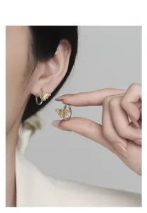 Detailed view of bicolor silver and gold butterfly hoop earrings with fine texture