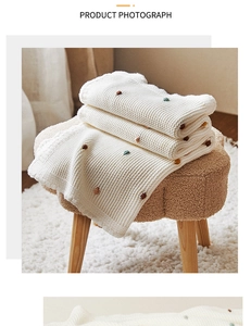 Detail of cream knitted throw blanket with colorful dots and wavy crochet edges