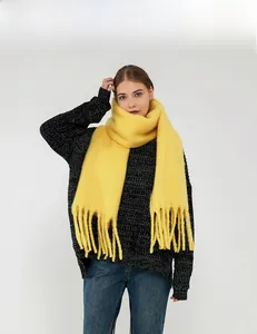 Detail showing bright yellow mohair scarf with tassels paired with grey knit sweater