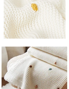 Detailed macro view of the cream white knitted blanket with colorful embroidered dots