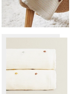 Detail of white cotton knit throw blanket with colorful embroidered polka dots texture
