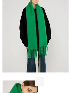 Close-up of vibrant green scarf showing soft knit texture and long tassel details