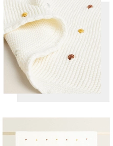 Detail of white knit throw blanket featuring colorful polka dots and thick texture