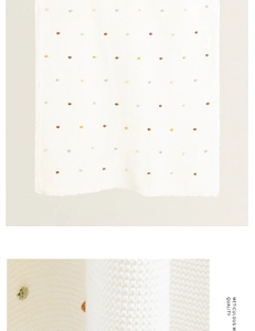 Detail of white waffle knit cotton blanket with colorful polka dots and soft texture