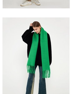 Detail of bright green knit scarf with long fringe tassels on high-quality cashmere-like fabric