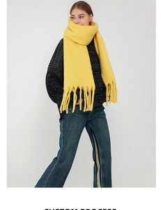 Close-up of bright yellow thick mohair scarf with long tassels and soft fluffy texture