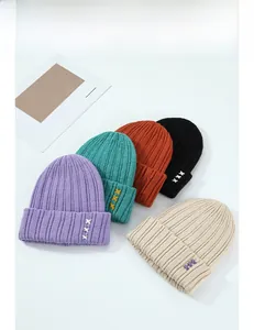 Détail de bonnets en tricot multicolores avec broderie triple-X et texture côtelée