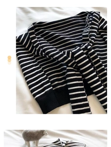 Detail of black and white striped knit shawl featuring elegant front tie and soft texture