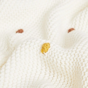White cotton knit throw blanket with decorative pom-poms for cozy sofa home decor