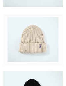 Détail du bonnet en maille côtelée beige avec broderie croix violette sur le revers