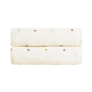 Minimalist ivory cotton knit blanket featuring colorful pom-pom dots and delicate texture