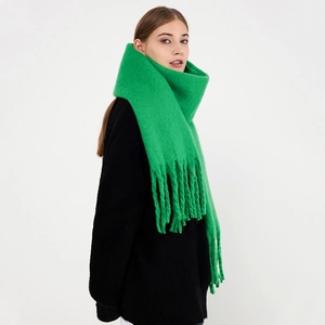 Green thick knit mohair scarf with long tassels worn over a black winter wool coat