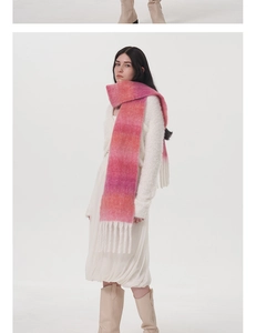 Dettaglio della sciarpa in lana mohair sfumata rosa con spesse nappe bianche su outfit invernale