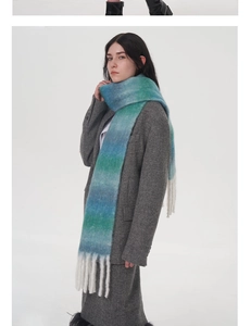 Dettaglio della sciarpa in lana sfumata blu-verde con nappe bianche e consistenza mohair