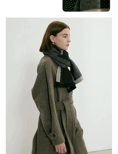 Gros plan d'une écharpe chaude en tricot jacquard à pois avec un manteau en laine camel