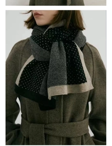 Détail d'une écharpe en maille à pois gris et noirs avec des bords contrastés beiges élégants