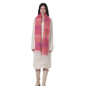 Sciarpa in mohair sfumata rosa e arancione con nappe bianche indossata da un modello