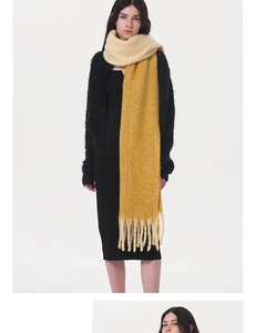 Detail of yellow knit scarf showing thick soft texture and long fringe tassels
