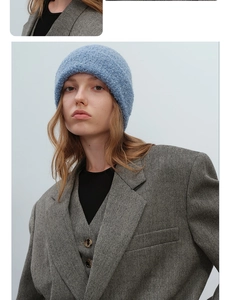 Detail of light blue textured bouclé knit beanie paired with a grey herringbone blazer