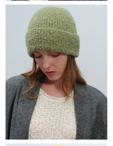 Detailed texture of moss green bouclé knit beanie on model with elegant minimalist style