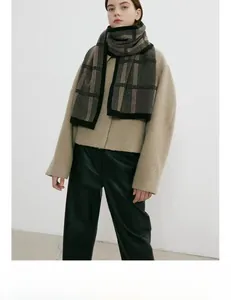 Detail of a thick plaid knit scarf featuring a wide black border and a minimal aesthetic