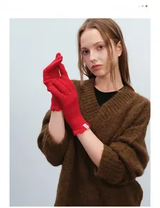 Detail of red wool knit gloves with elegant wavy ruffled cuffs and cozy thick texture