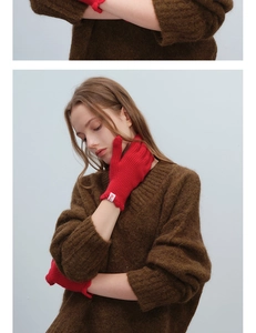 Detail of red wool knit gloves with vertical ribs and a small woven wrist label