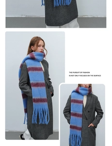 Detail view of sky blue and burgundy striped scarf with fringe on grey coat