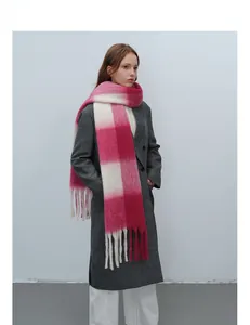 Nahaufnahme von rosa-beigem Karo-Schal mit langen Fransen auf grauem Wollmantel