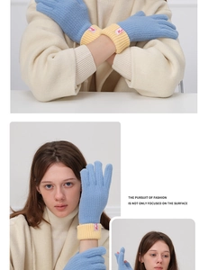 Detail view of light blue wool knit gloves with yellow ribbed cuffs and a side brand label
