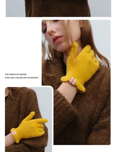 Detail of bright yellow wool knit gloves featuring a logo patch and soft thermal texture