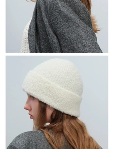 Detail of soft white textured wool knit beanie paired with a classic grey herringbone coat