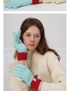 Detail of wool blend knitted gloves with mint green body and red ribbed cuffs